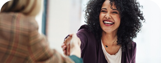 Two women smiling and shaking hands