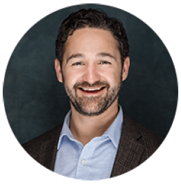 Headshot of a smiling man with a beard in a blazer