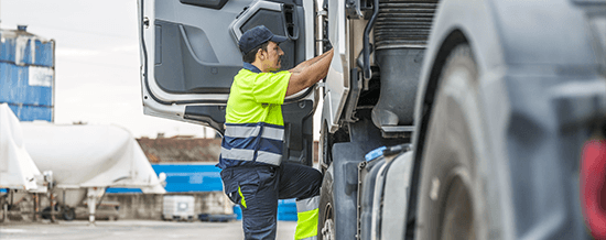 Logistics worker in a high-visibility vest inspecting a truck at a shipping site