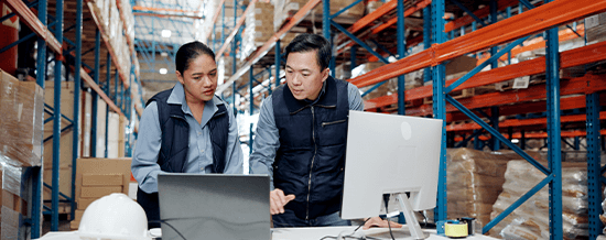 Two workers reviewing information on a computer in a warehouse