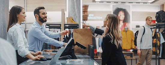 Cashier assisting customers at a retail clothing store checkout