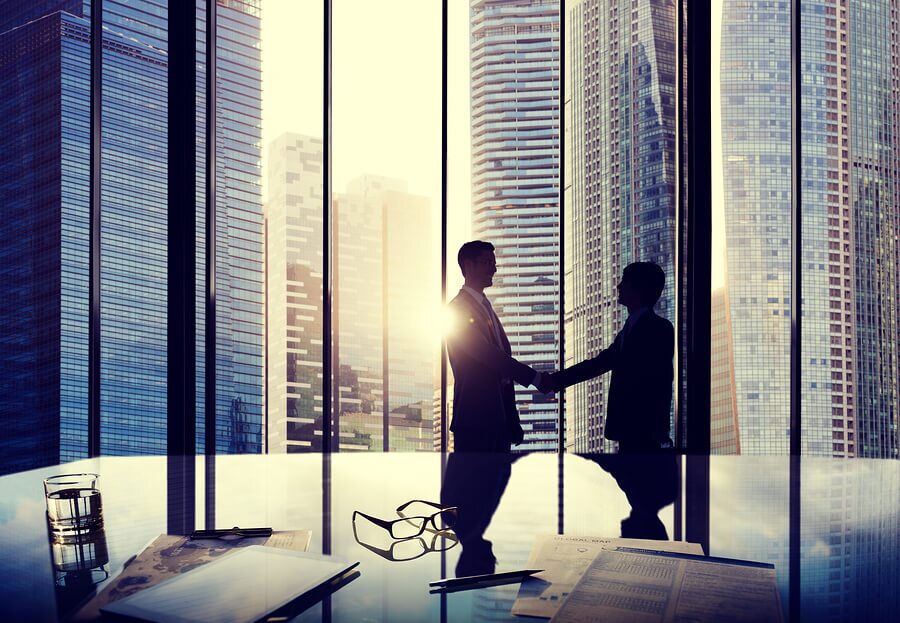 Men having a handshake next to large cityscape