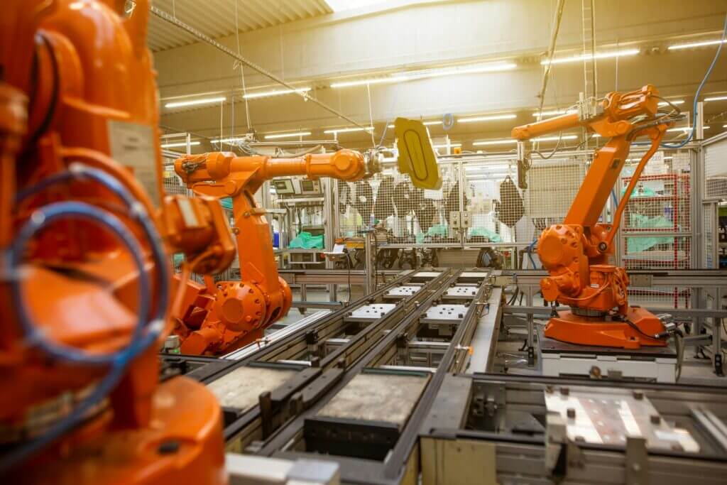 Row of orange industrial robotic arms on a factory assembly line