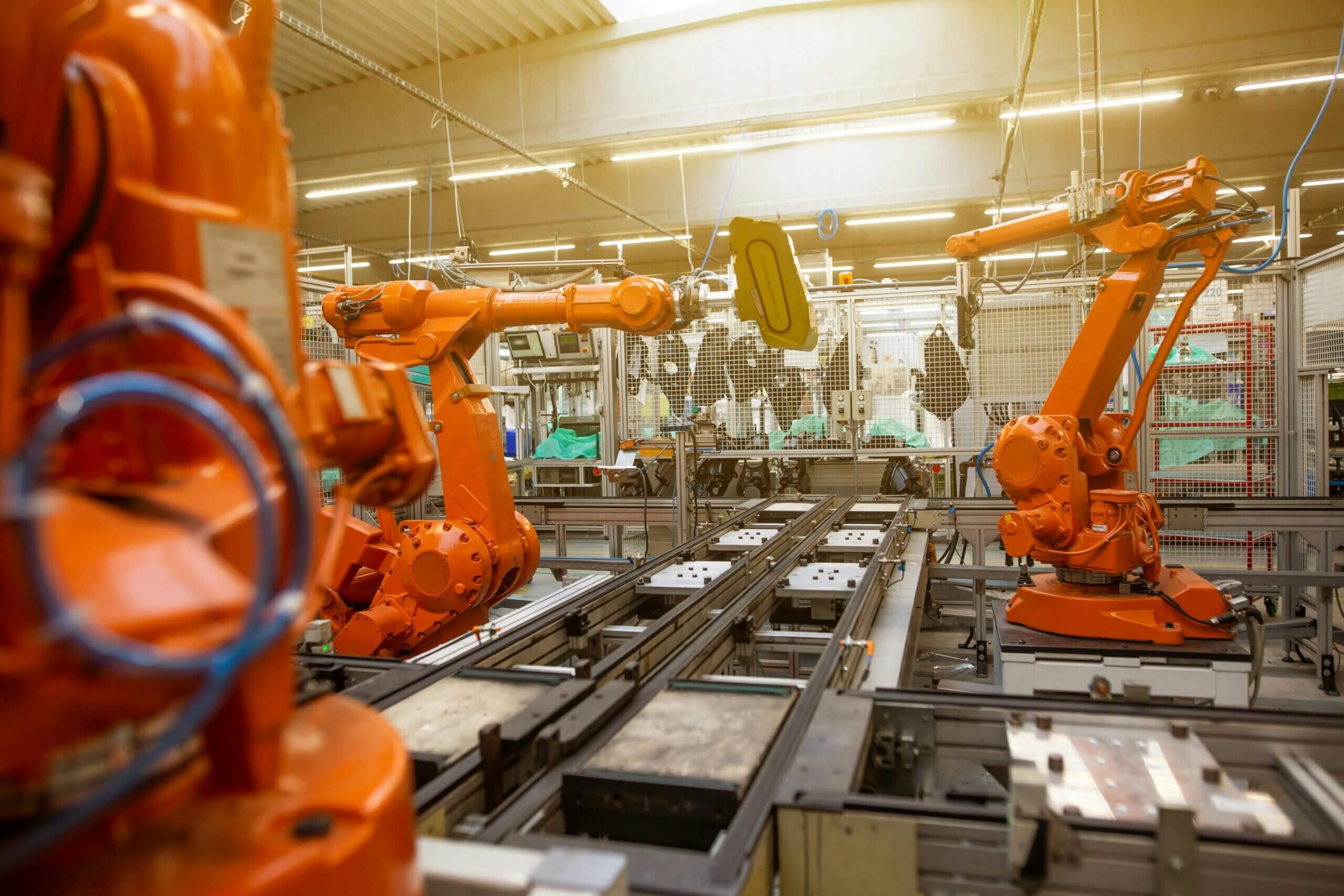 Row of orange industrial robotic arms on a factory assembly line