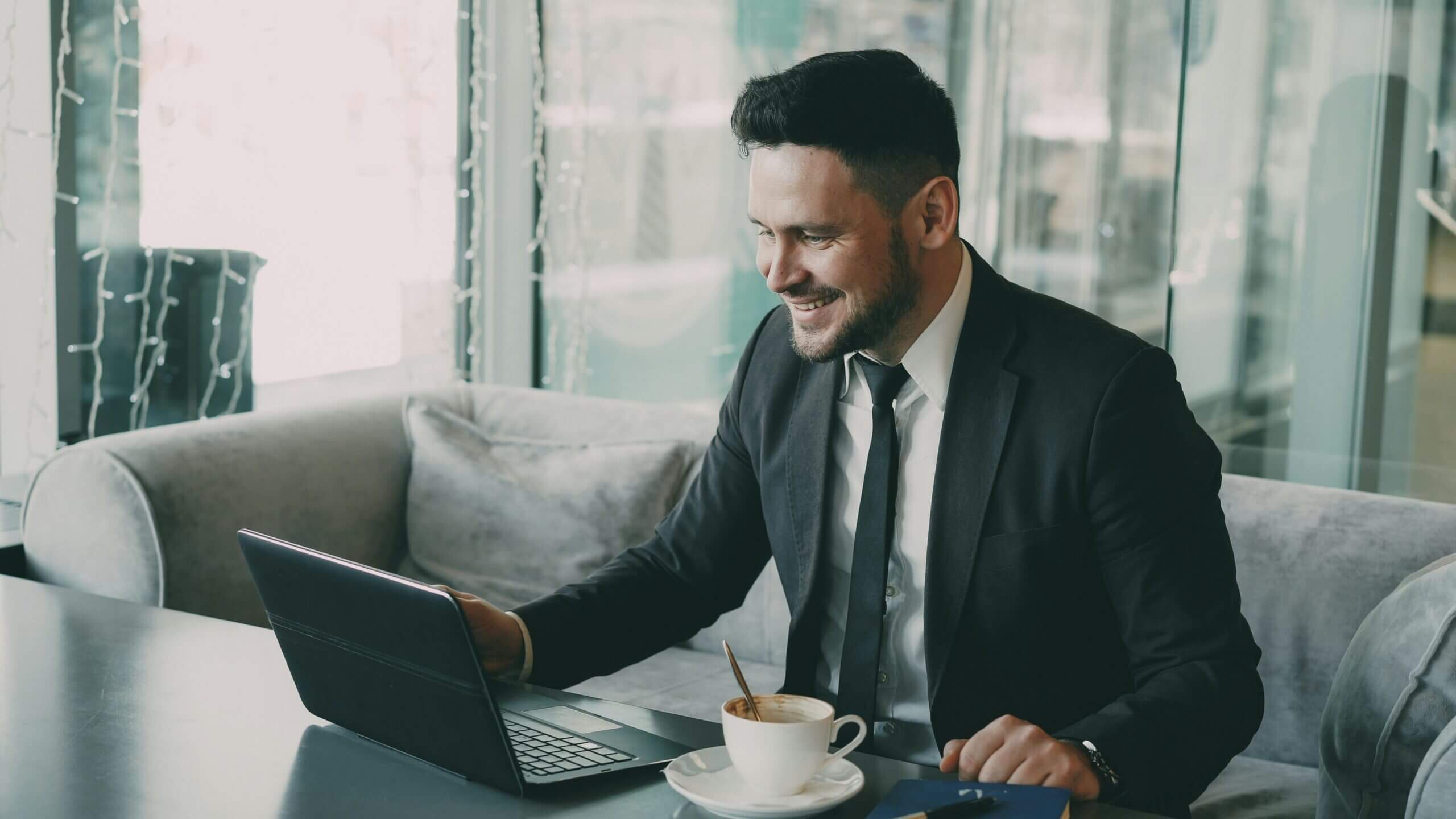 Smiling businessman in a suit looking at his computer while reviewing long term incentive plans