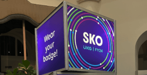 Conference digital signage reading 'Wear your badge' at UKG SKO FY24