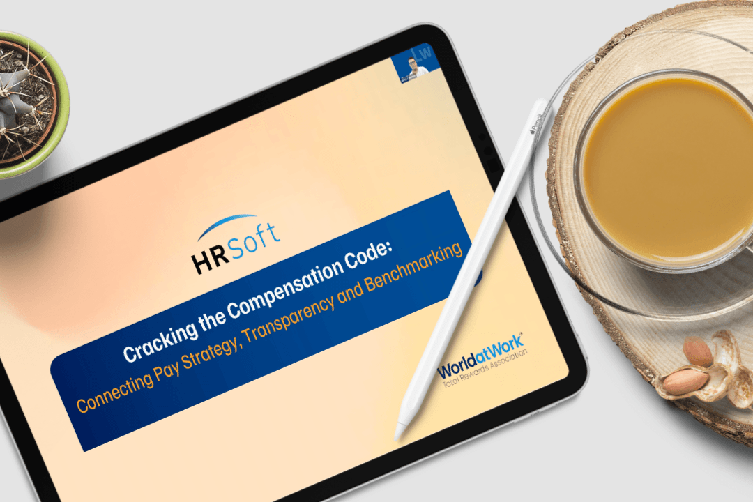 Tablet displaying an HRSoft 'Cracking the Compensation Code' presentation on a desk