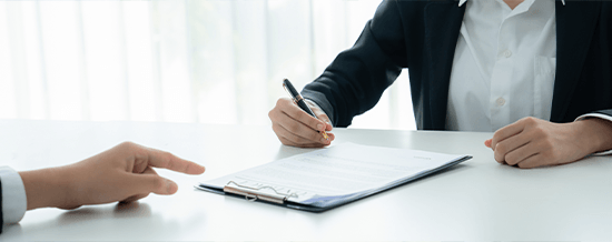 Two people reviewing and signing a document at a desk