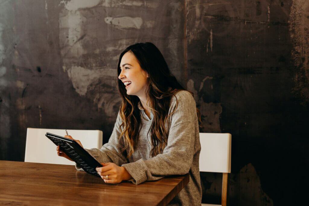 Smiling woman holding a tablet while seated at a table
