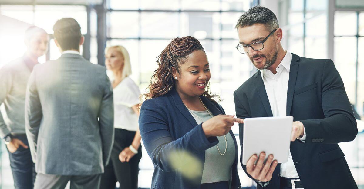 Two business professionals review compensation data on a tablet, symbolizing executive pay planning and strategies for aligning rewards with company goals