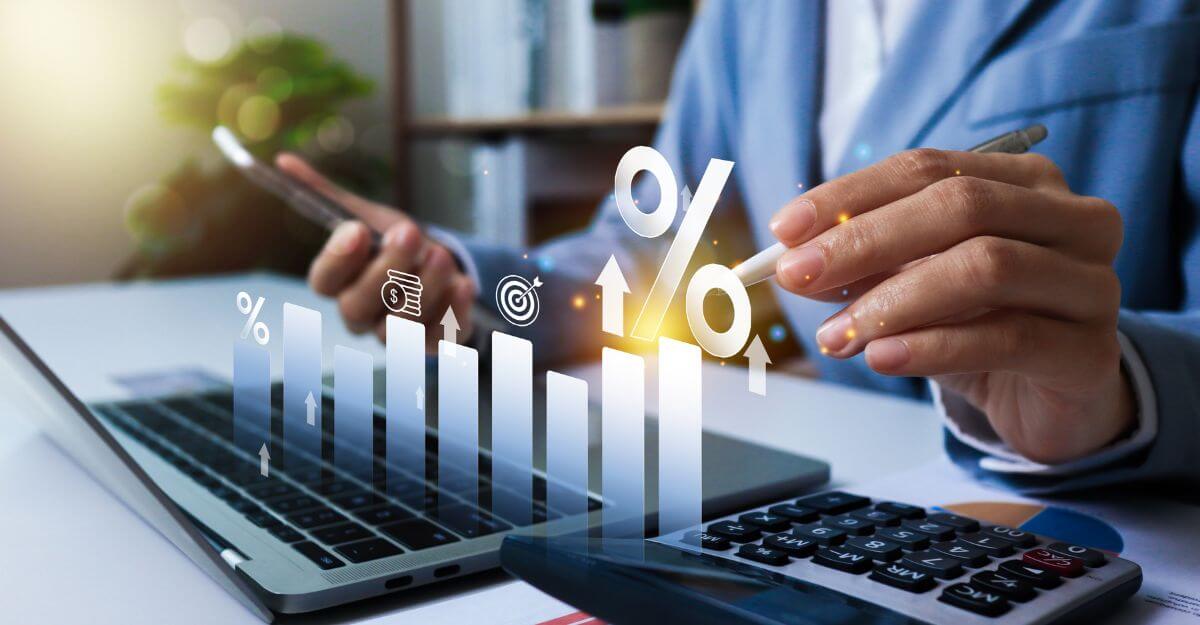 Professional analyzing compensation and total rewards trends, with digital charts showing rising pay, incentives, and performance metrics on a laptop and calculator.