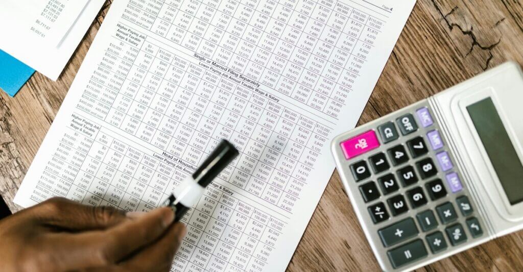 Hand writing beside a calculator over financial documents