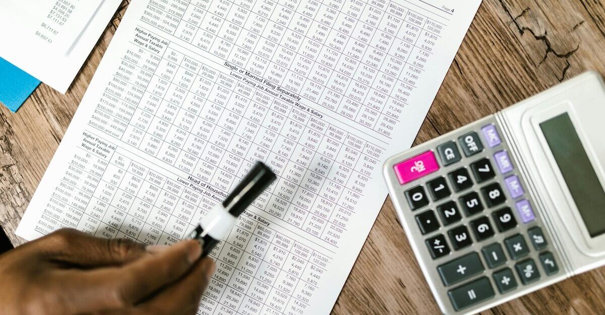Hand writing beside a calculator over financial documents