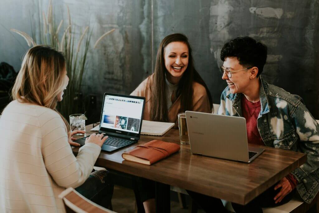 Three women collaborating with laptops at an office table