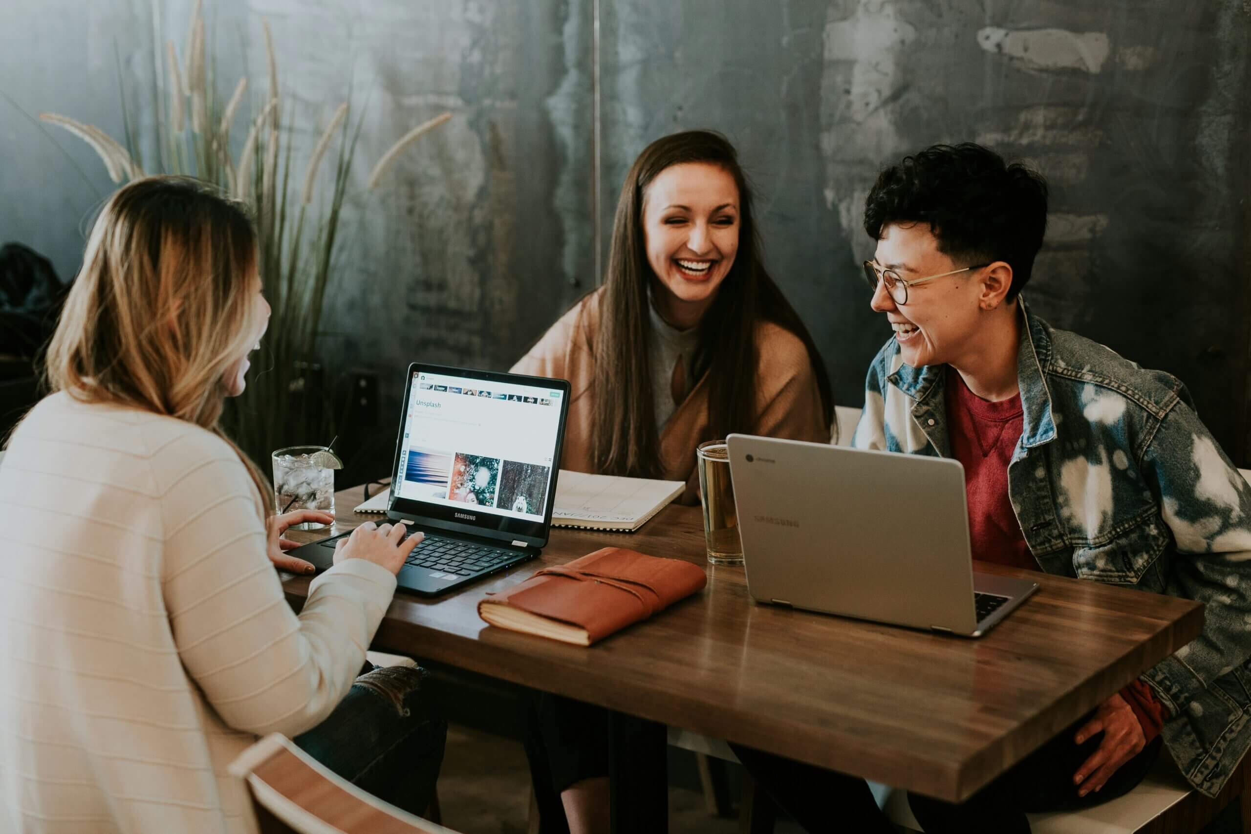 Three women collaborating with laptops at an office table