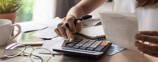 Hands using a calculator with a receipt on a desk